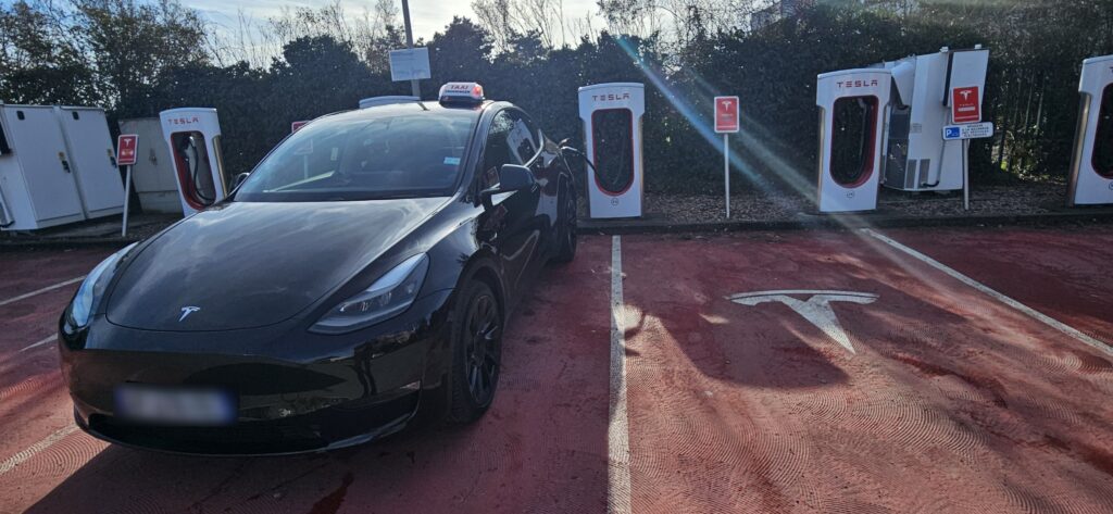 Taxi Tesla branché à une borne de recharge.