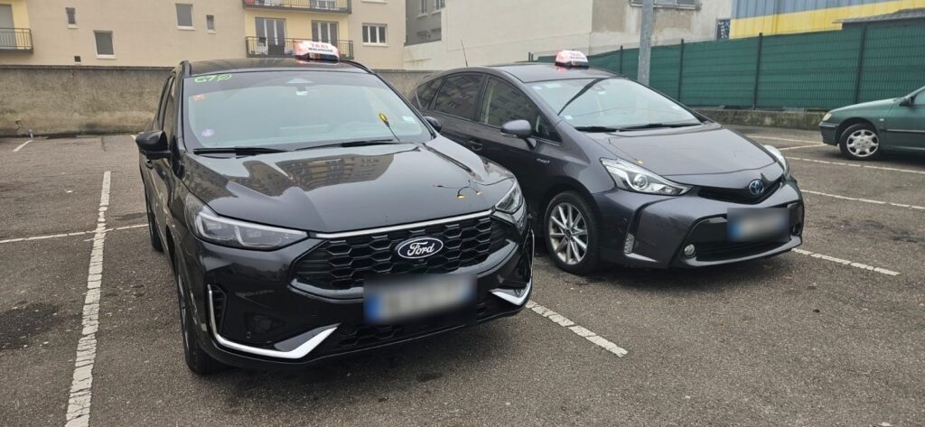 Deux taxis Ford et Toyota stationnés côte à côte.
